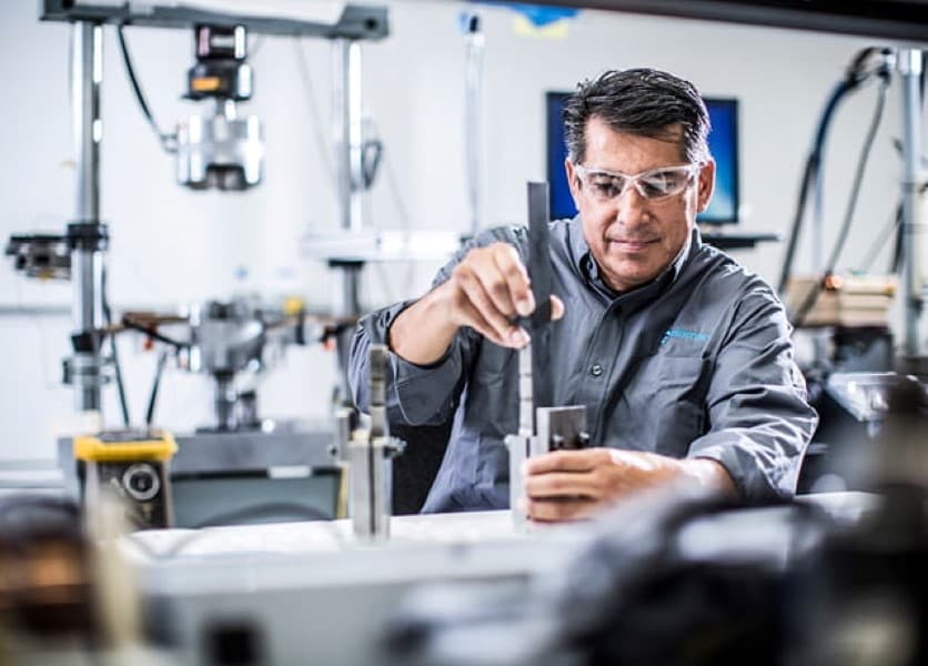 Element testing engineer studying a testing sample at a work bench 